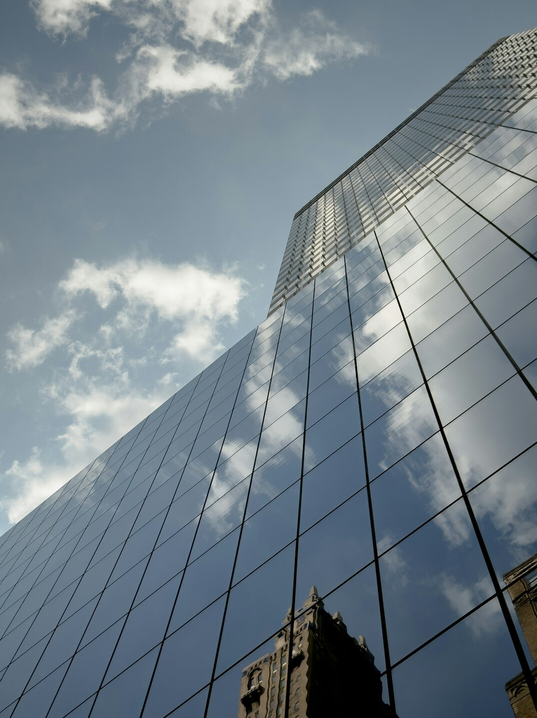 Glass office building facade reflecting clouds